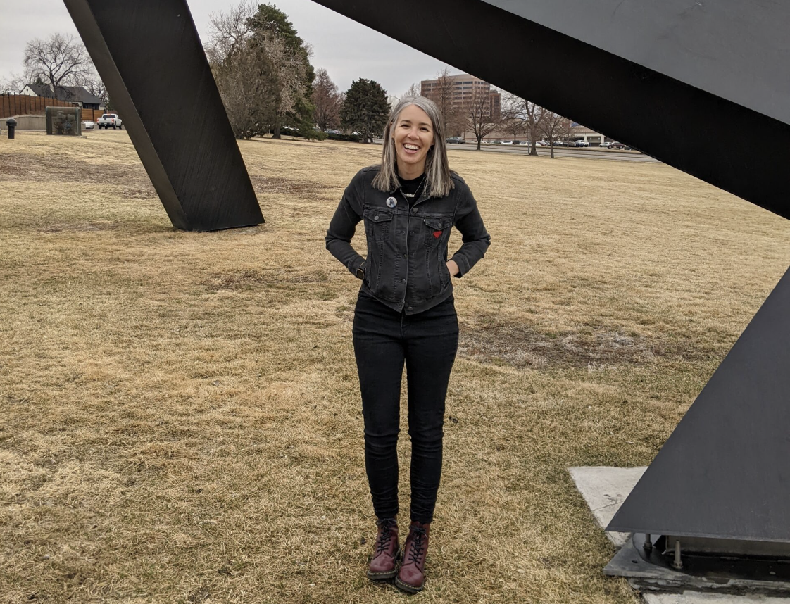 Alison is standing outside in front of a large black sculpture at a park.